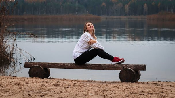 Joven dama se sienta en el lago berigu y mira al lago - Foto, Imagen