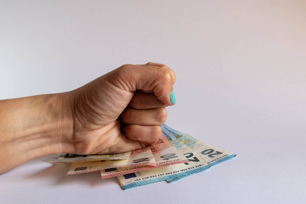 Энергетически сжатый кулак на некоторых банкнотах евро на белом фоне - Фото, изображение
