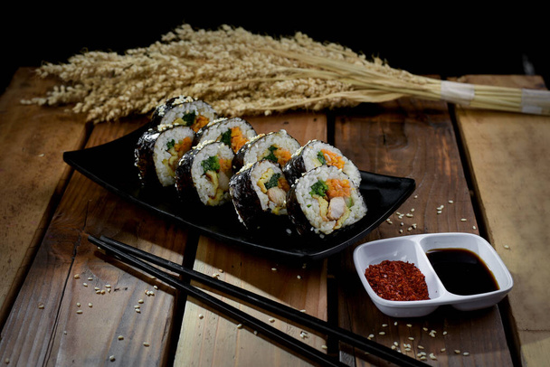 Гимбап - это корейская еда, состоящая из риса, завернутого в морские водоросли. Гимбап популярен как блюдо, которое приносят с собой на пикники, прогулки или другие мероприятия на свежем воздухе. - Фото, изображение