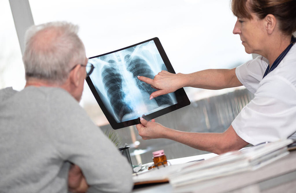 Médecin féminin montrant des rayons X à sa patiente au cabinet médical - Photo, image
