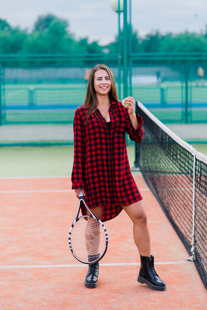 Bella donna sexy elegante in un nero alla moda abbigliamento sportivo sul campo da tennis. - Foto, immagini