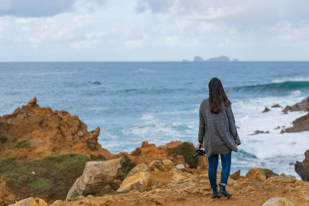 Кавказская женщина смотрит на остров в океане со скалы в Пенише, Португалия - Фото, изображение