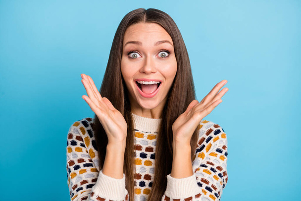 Photo of surprised funny young woman dressed ornament pullover rising arms hands isolated blue color background - Zdjęcie, obraz