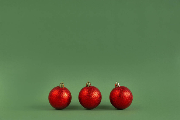 green shiny Christmas balls on a green background. New year and christmas concept. Minimal festive composition. copy space for text. - Фото, зображення