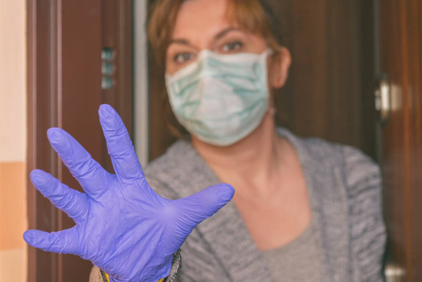 Mulher vestindo uma máscara protetora abrindo portas de sua casa por causa de uma epidemia de corona vírus covid-19. Quarentena em casa e conceito de auto-isolamento - Foto, Imagem