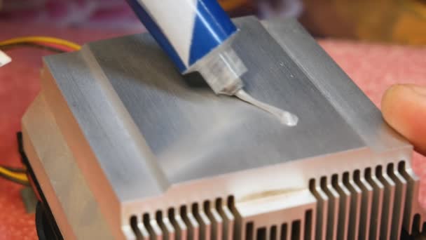 Aplicação e distribuição de pasta térmica de um tubo para um radiador de refrigeração de PC. Close-up do processo de reparação preventiva e eliminação do superaquecimento do equipamento - Filmagem, Vídeo