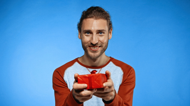glücklicher bärtiger Mann mit umwickeltem Geschenk auf blauem Grund - Foto, Bild