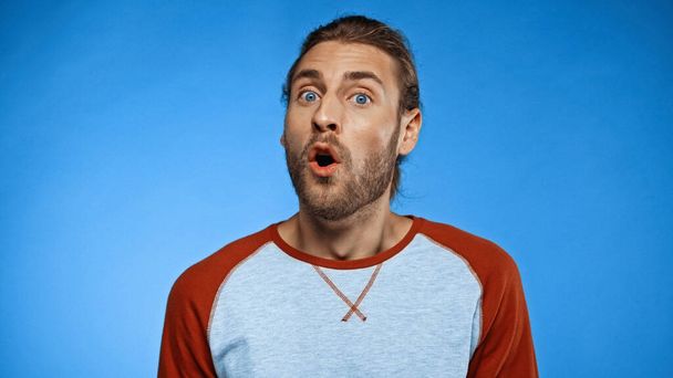shocked and bearded man with open mouth looking at camera on blue - Фото, зображення