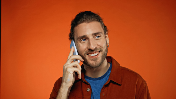 jovem feliz falando no telefone celular em laranja  - Foto, Imagem