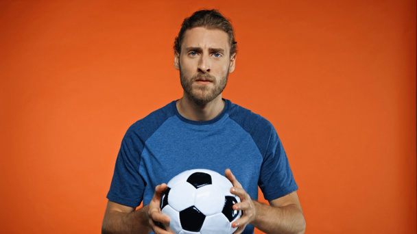 football fan in blue t-shirt holding soccer ball on orange  - Φωτογραφία, εικόνα