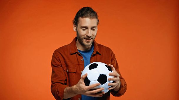 happy football fan looking at soccer ball on orange  - Zdjęcie, obraz