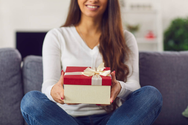 Smiling brunette girl holding holiday present box in hands during online dating - Photo, Image