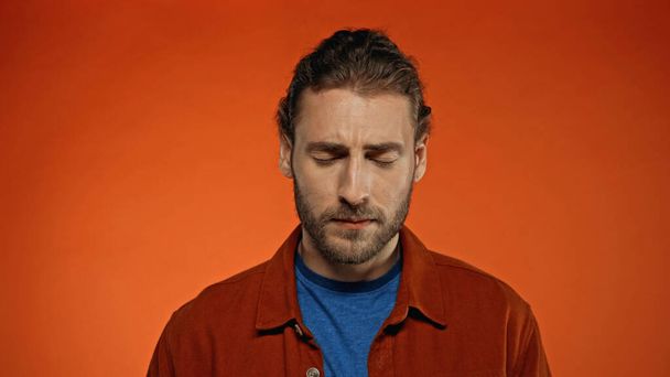 young bearded man with closed eyes on orange background  - Foto, imagen