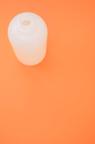 A vertical shot of a plastic bottle on an orange background - Фото, зображення
