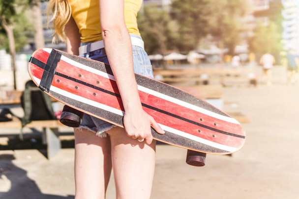 Een blanke vrouw in jeans met een skateboard - Foto, afbeelding