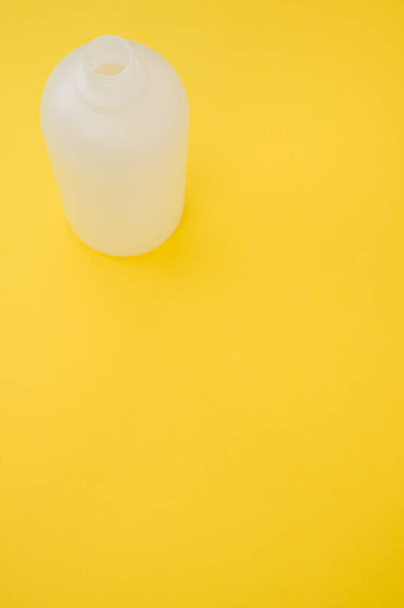 黄色の背景にプラスチックボトルの垂直ショット - 写真・画像