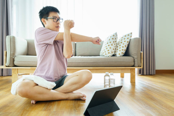 Új normál edzés otthon Egy 35-40 éves ázsiai férfi, barna bőrrel, házi gyakorlattal. gyakorlás a nappaliban. - Fotó, kép