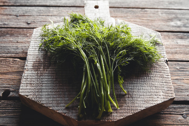 Fresh green dill on the wooden cutting board closeup. Fresh herbal condiment dill  - Foto, immagini