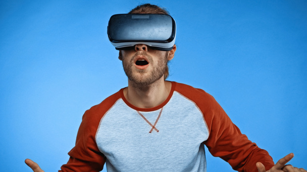 šokovaný mladý muž ve virtuální realitě sluchátka na modré  - Fotografie, Obrázek