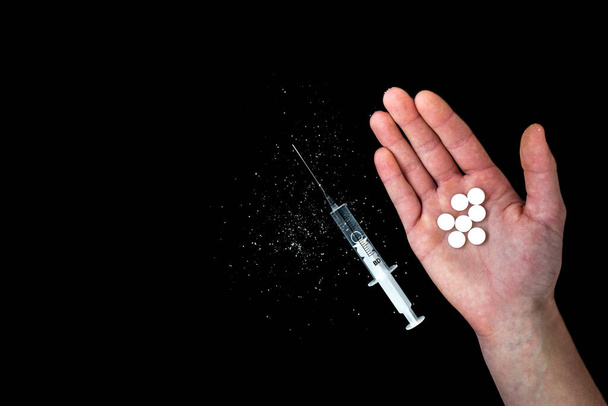 Seringue et pilules blanches sur fond noir. Concept d'abus de drogues. Stupéfiants. Traitement - Photo, image