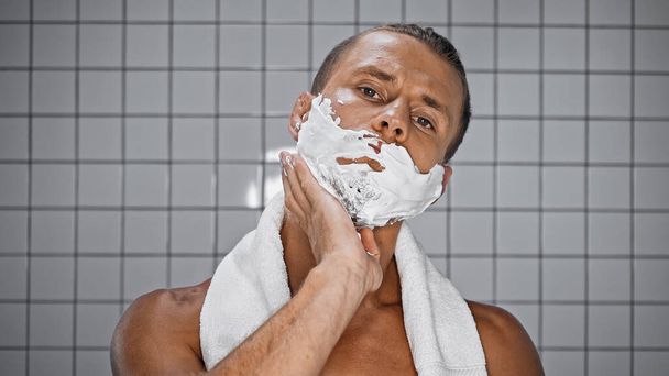 shirtless man applying shaving foam in bathroom - Фото, изображение