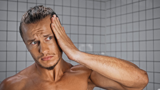 félmeztelen fiatalember rögzíti haj a fürdőszobában  - Fotó, kép