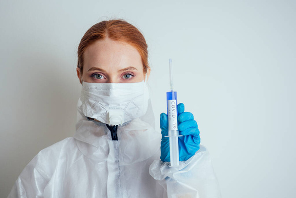 virologist woman in chemical protection mask ,glasses and gloves holding potential vaccine at the lab - Photo, image