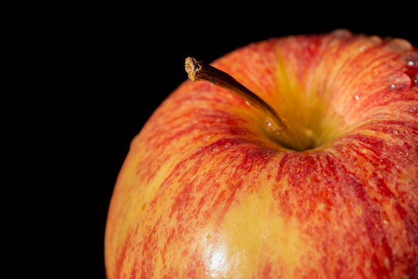 Makro zbliżenie wierzchołka czerwonego jabłka z kroplami wody, ostrość selektywna, na czarnym tle, pozioma - Zdjęcie, obraz