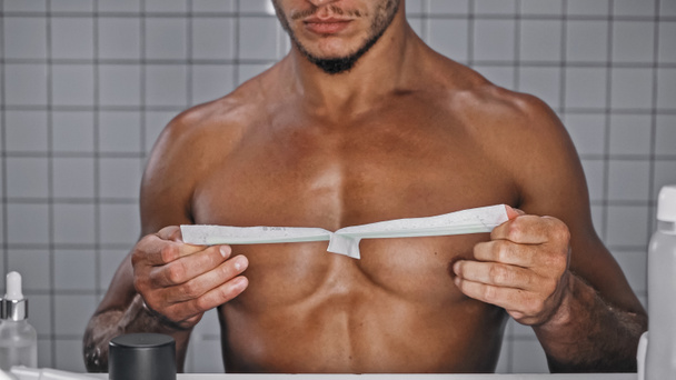 partial view of shirtless man holding wax strip on chest in bathroom  - Foto, afbeelding