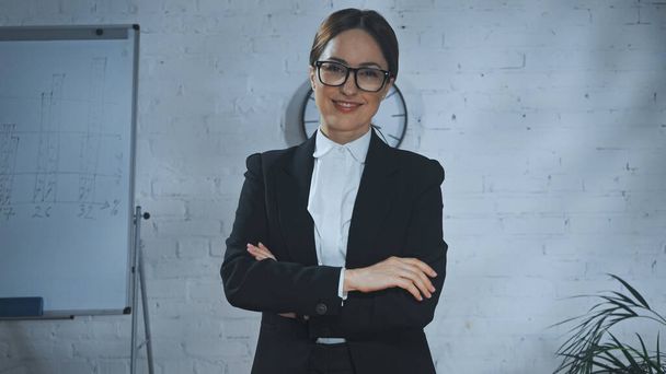 Smiling insurance agent with crossed arms looking at camera in office  - Photo, image