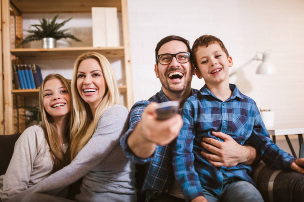 Счастливая семья вместе смотрит телевизор дома и веселится вместе. - Фото, изображение