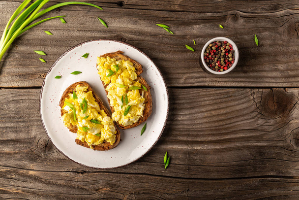 Breakfast with scrambled eggs on wholewheat toast. English breakfast with fried egg. banner, menu, recipe, place for text. - Photo, Image