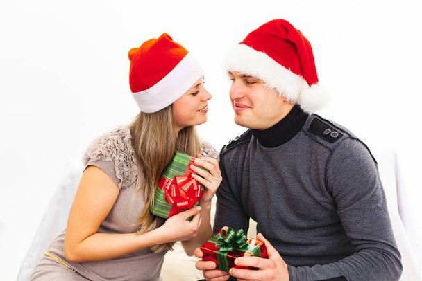 Couple in love in santa hats with christmas gifts, on a white background - Fotó, kép