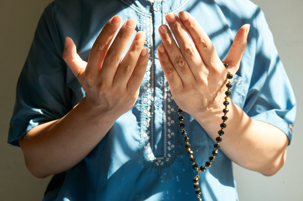 Muslimischer Mann hebt beide Hände zum Gebet mit schwarzen Gebetsperlen - Foto, Bild