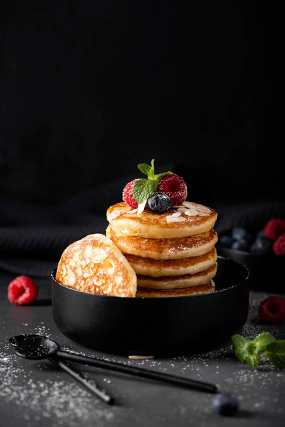 small thin pancakes with fresh berries and honey in a black bowl, close-up - Photo, image