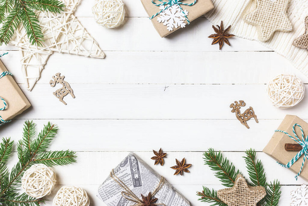 クリスマスや冬の構図。白い木製の背景にクリスマスプレゼント、モミの木の枝、ニット毛布や装飾品。フラットレイアウト、トップビュー、コピースペース. - 写真・画像