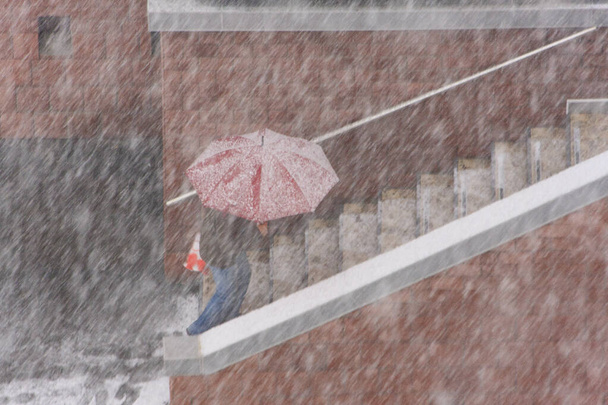 image floue - une personne grimpant sous un parapluie rouge sur les marches image floue - un homme marchant sous un parapluie rouge en chute de neige - Photo, image
