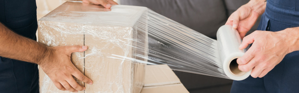 vista recortada de movers caja de embalaje con película elástica, pancarta - Foto, Imagen