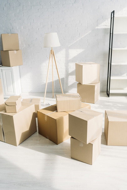 stack of carton boxes near floor lamp in modern apartment  - Photo, Image