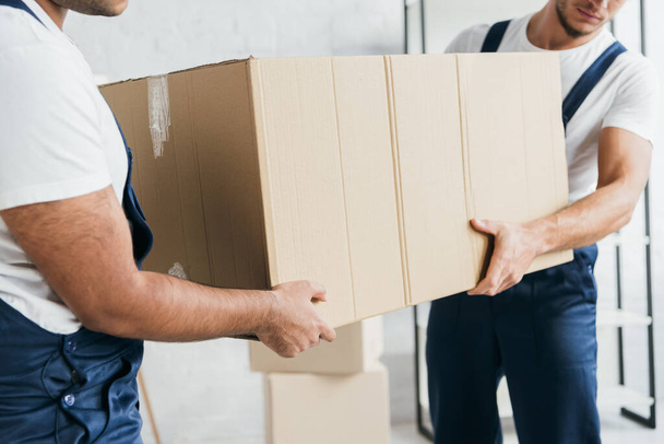 partial view of multiethnic movers holding carton box  - Foto, Imagen