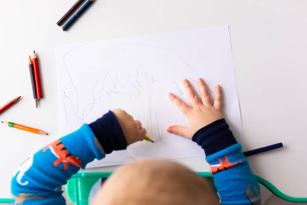 Left handed baby boy drawing a picture with colored pencils - Foto, afbeelding