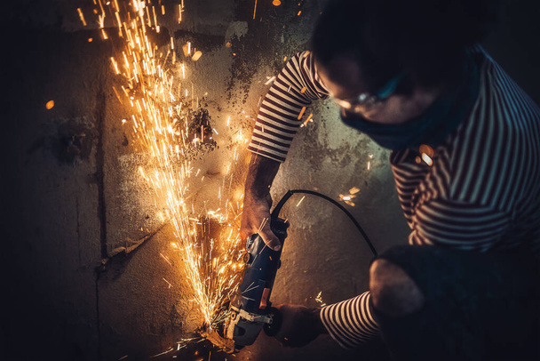 Trabajador de corte de metal con amoladora. Chispas mientras moliendo hierro. - Foto, Imagen