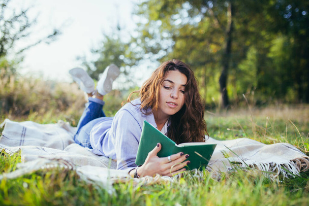 Nostalgiczna nastolatka siedzi w parku i czyta książkę - Zdjęcie, obraz