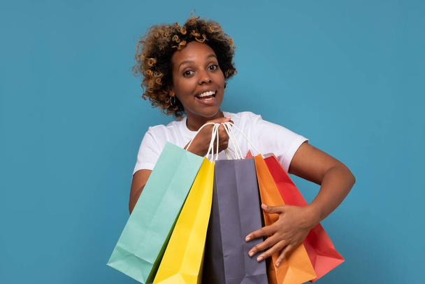 Jovem mulher africana bonita com sacos de compras coloridos sendo animado com suas compras. - Foto, Imagem