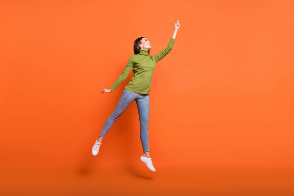 Full length photo of young active woman happy smile try catch umbrella jump isolated over orange color background - Fotó, kép