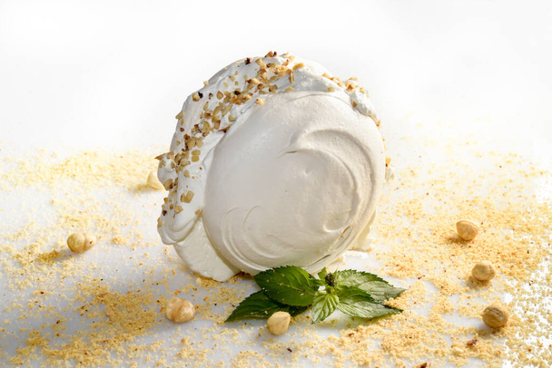 whipped cream-filled meringue with chopped hazelnuts and mint leaves on a white background - Photo, Image