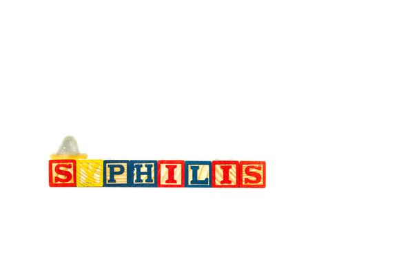 Wooden toy blocks spell out Syphilis with a condom sitting on one block. Isolated on white background. High quality photo - Photo, Image