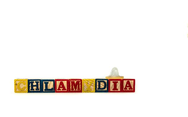Drewniany blok alfabetu literuje słowo Chlamydia, z prezerwatywą na jednym z bloków. Odizolowany na białym tle. Wysokiej jakości zdjęcie - Zdjęcie, obraz