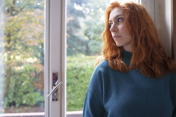 Portrait of pensive woman standing beside window - Photo, Image