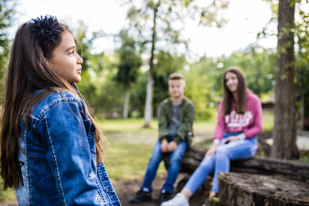 Portré boldog kislányról, miközben a barátaiddal beszélgetsz a parkban. - Fotó, kép